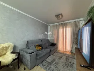 Sala de estar com sofá cinza e televisão em um apartamento.