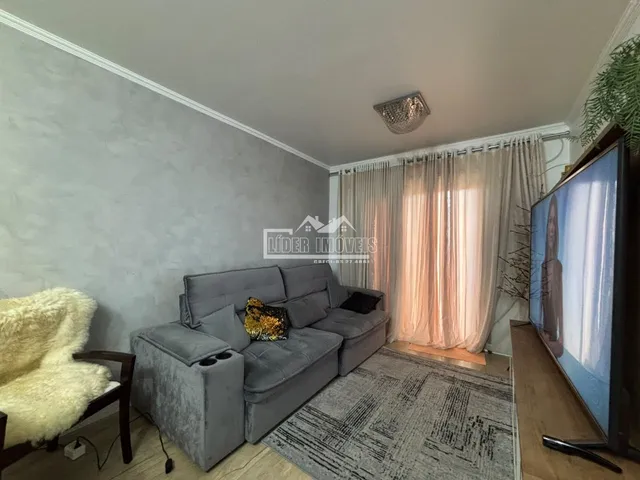Sala de estar com sofá cinza e televisão em um apartamento.