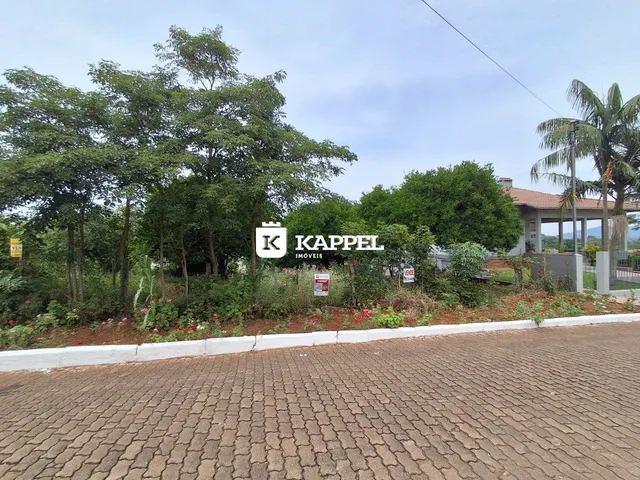 Vista externa de uma propriedade em Lajeado, com vegetação e uma área pavimentada em primeiro plano.