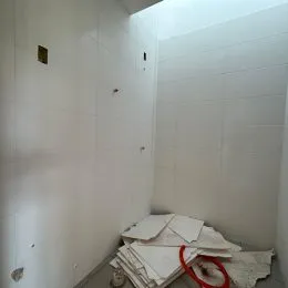 Foto de um interior com paredes brancas e roupas dobradas no chão.