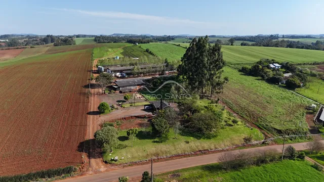 Vista aérea de uma propriedade rural com campos verdes e vegetação.