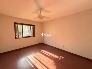 Sala de estar com piso de madeira e janela no interior de uma residência.