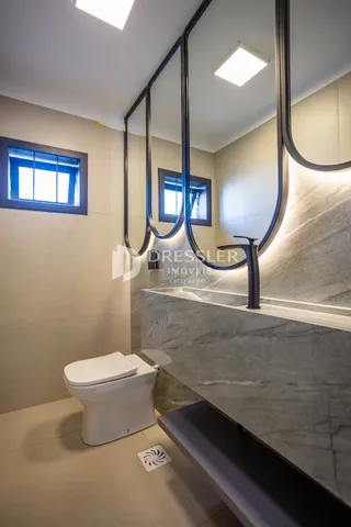 Interior de um banheiro com bancada de mármore e vaso sanitário branco.
