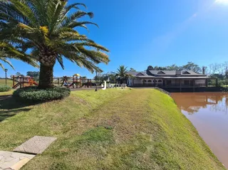 Vista externa de um terreno com gramado e corpo d'água.