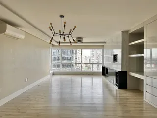 Sala de estar ampla com piso de madeira clara e grande janela.