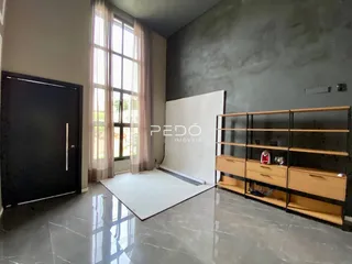Interior de uma sala com grande janela e parede de concreto aparente.