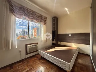 Quarto com vista para a cidade e piso de madeira.