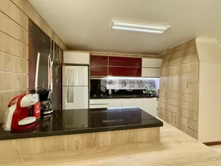 Foto de uma cozinha moderna com armários brancos e detalhes em vermelho.