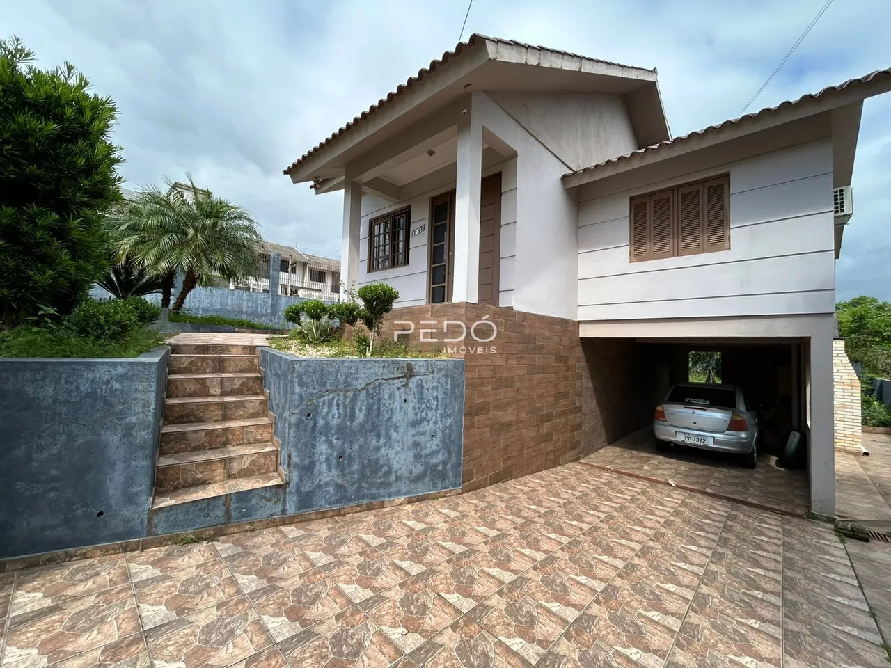 Fachada de uma residência em Lajeado, Brasil, com escadaria e área externa pavimentada.