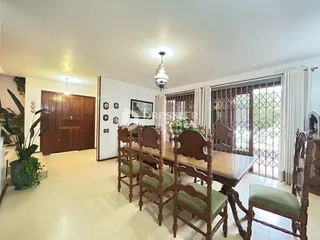 Sala de jantar com mesa de madeira e cadeiras que se abre para uma área externa.