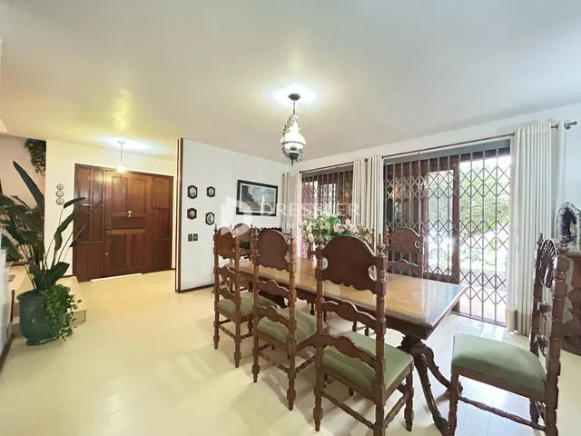 Sala de jantar com mesa de madeira e cadeiras que se abre para uma área externa.