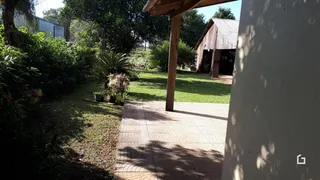 Vista externa de um jardim com um caminho de tijolos e uma estrutura de madeira.