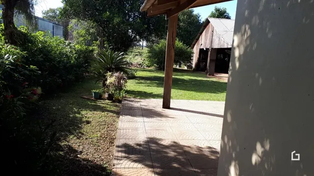 Vista externa de um jardim com um caminho de tijolos e uma estrutura de madeira.