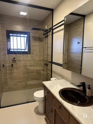 Foto de um banheiro com box de vidro e revestimento de cerâmica.