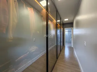 Hall de corredor interno com piso de madeira e espelho refletindo um ambiente.