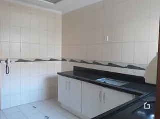 Interior de uma cozinha com revestimento de cerâmica branca e bancada escura.
