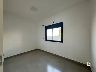 Foto de um ambiente interno vazio com paredes brancas e piso cinza.