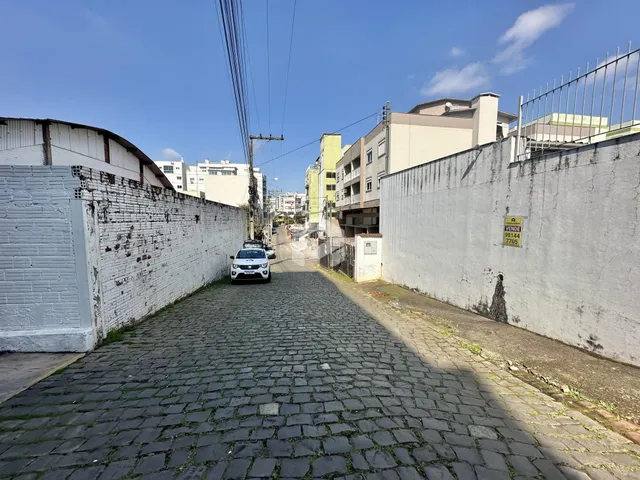 Vista de uma rua pavimentada com paralelepípedos entre duas paredes laterais.