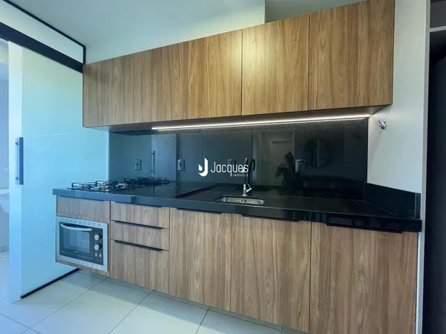 Cozinha moderna com armários de madeira e bancada preta.