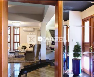 Vista interna de uma sala de estar com piso de madeira e sofá.