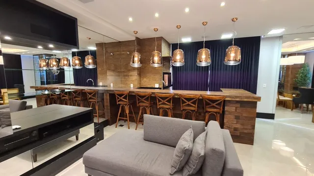 Sala de estar com sofá grande e piso de madeira aparente.