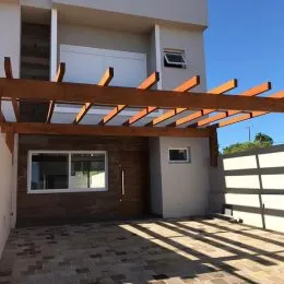 Fachada de uma residência com estrutura de madeira sobre uma área externa.
