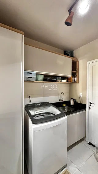 Foto de uma cozinha interna com armários brancos e bancada escura.
