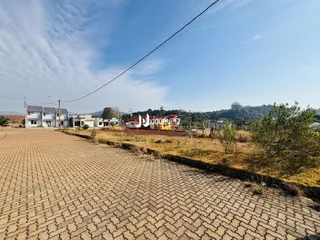 Vista externa de um terreno pavimentado com tijolos e vegetação seca.