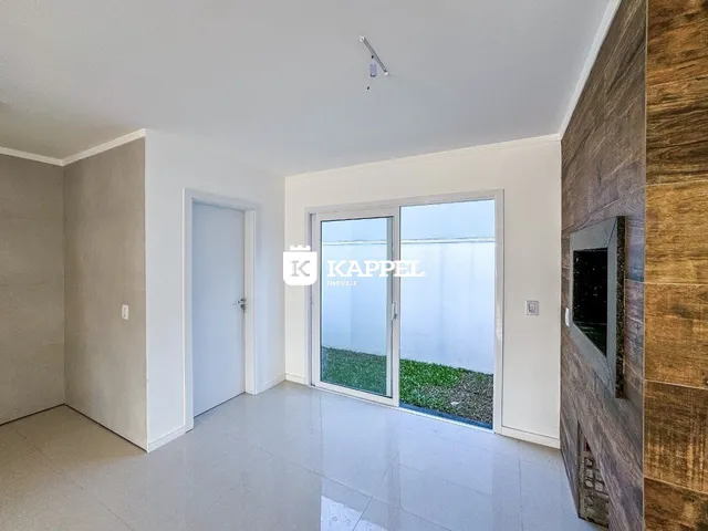 Sala de estar com piso claro e porta de vidro que dá acesso a um jardim.