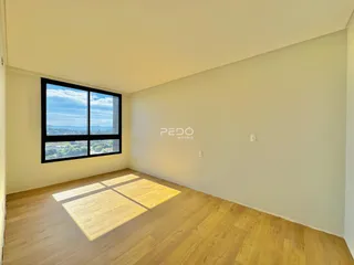 Sala de estar com piso de madeira e grande janela com vista.