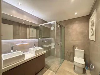 Foto de um banheiro moderno com bancadas brancas e box de vidro.