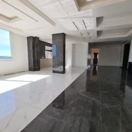 Vista interna de um ambiente amplo com piso escuro e teto branco.