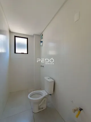 Foto de um corredor interno com paredes brancas e um vaso sanitário.