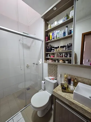 Banheiro com box de vidro e bancada de granito.