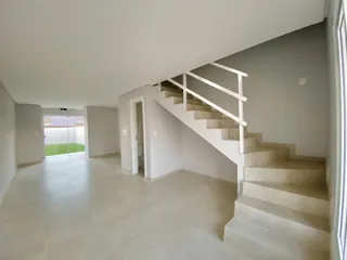 Hall de entrada com escadaria branca em um ambiente claro.