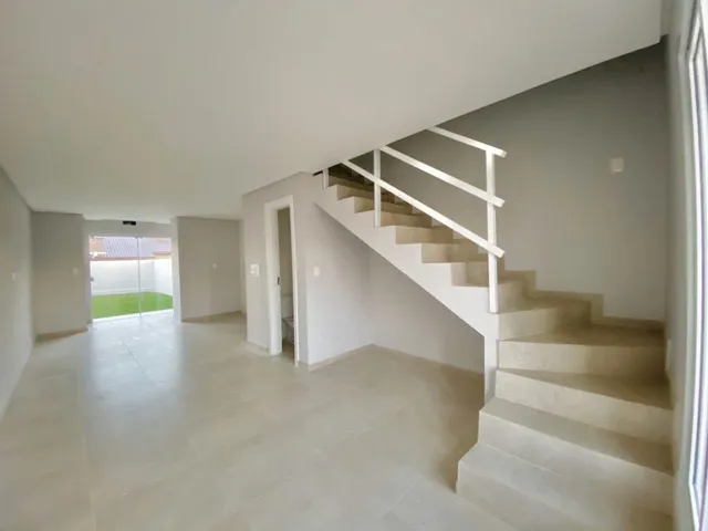 Hall de entrada com escadaria branca em um ambiente claro.