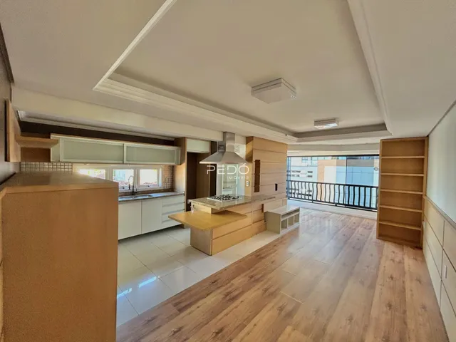 Ambiente de sala e cozinha com piso de madeira e vista para a varanda.