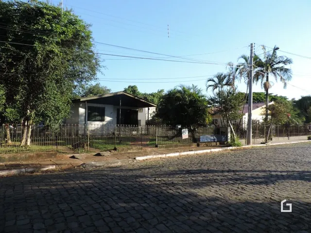 Vista externa de uma propriedade com cerca e vegetação ao fundo.