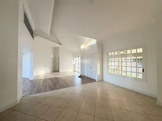 Ambiente interno amplo com piso de cerâmica e grande janela em uma residência.