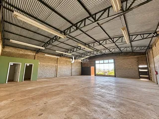 Espaço amplo de um galpão industrial com estrutura metálica e piso de concreto.