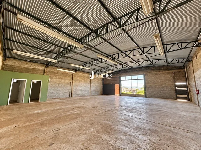 Espaço amplo de um galpão industrial com estrutura metálica e piso de concreto.