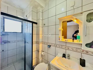 Foto de um banheiro com revestimento cerâmico e box de vidro.