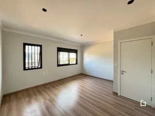 Ambiente interno de uma sala com piso de madeira clara e paredes brancas.