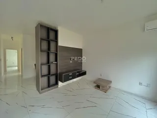 Sala de estar com piso de porcelanato claro e parede de destaque.