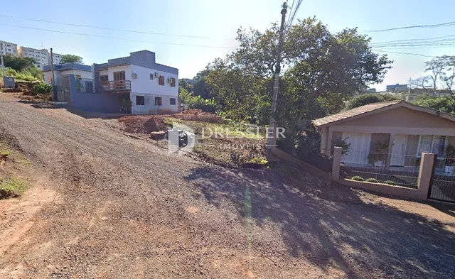Vista da propriedade com declive de terra e vegetação ao redor da casa.