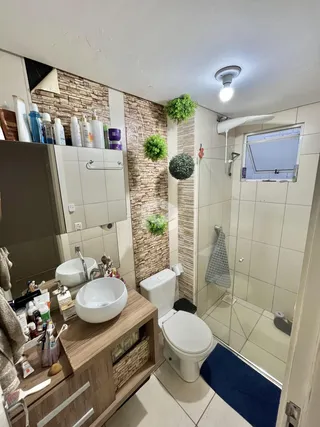 Foto de um banheiro com revestimento de azulejos brancos e detalhes em madeira.