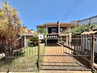 Fachada de uma residência em Lajeado, Brasil, com portão de ferro e jardim frontal.