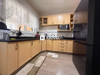 Cozinha com armários de madeira clara e bancada escura.