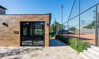 Fachada de uma residência com revestimento de madeira e área externa pavimentada.
