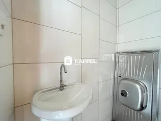 Foto de um lavabo com pia branca e revestimento de azulejos brancos.